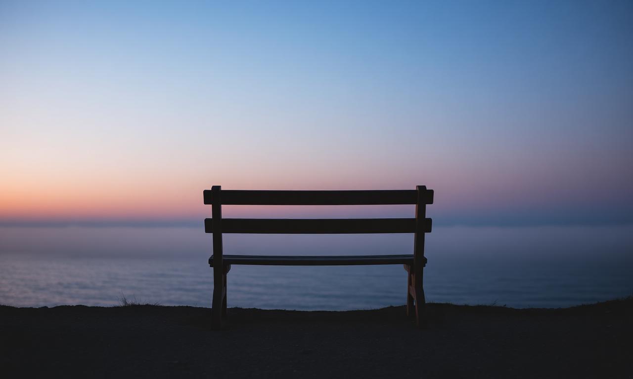 Empty wooden bench overlooking a quiet British coastline at twilight
